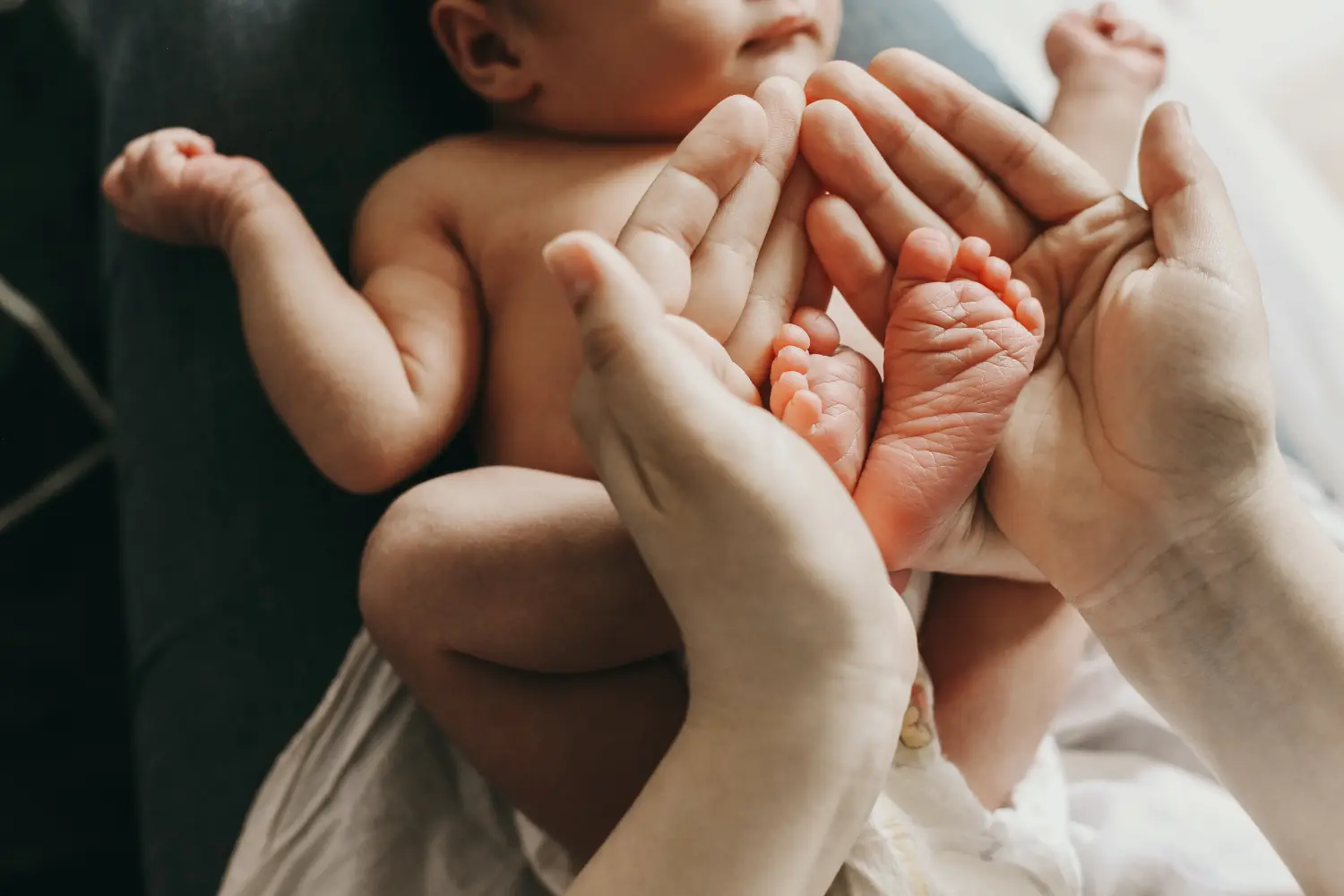 die Beine eines neugeborenen Babys in den Armen seiner Mutter